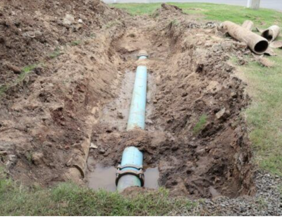 Underground utility construction — water and sewer pipe installation in a trench by Apex Professional Construction